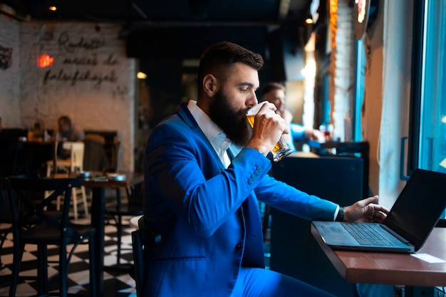 Un empresario con un portátil bebiendo cerveza en un pub