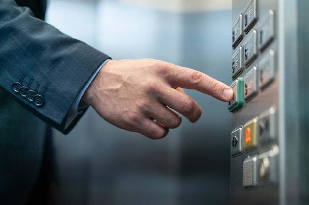 El empresario presiona el botón con braille para ciegos. Primer plano de la mano masculina caucásica presionando la tecla