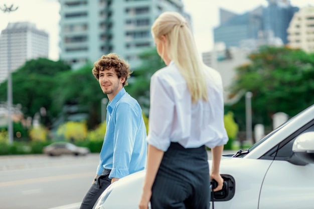 Empresario progresista y empresaria en el punto de carga y coche EV