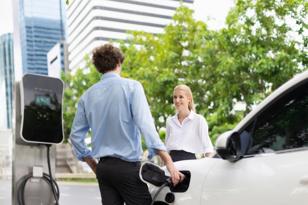 Empresario progresista y empresaria en el punto de carga y coche EV