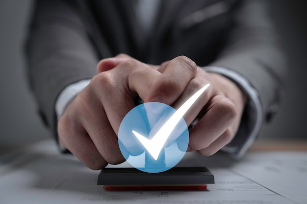 Empresario que lleva un sello de goma con un signo blanco correcto o una marca de verificación para el proyecto de documento aprueba y acepta el concepto del código de verificación