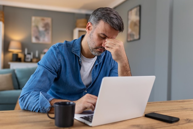 Empresario que trabaja en la oficina con dolor de cabeza por el escritorio que trabaja y está sentado todo el día usando una computadora portátil o un cuaderno que sufre dolor de cabeza trabajador enfermo concepto de exceso de trabajo