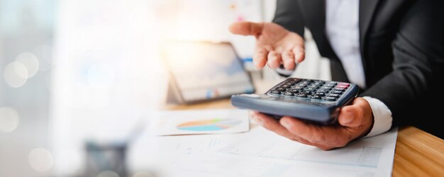 Empresario que usa la calculadora para calcular la contabilidad financiera