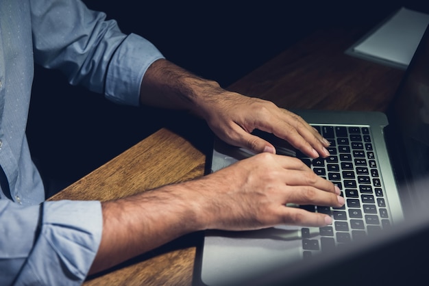 Empresario quedarse horas extra tarde por la noche trabajando con la computadora portátil