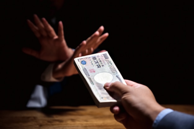 Empresário, recusando o dinheiro, moeda iene japonês, oferecido pelo seu parceiro