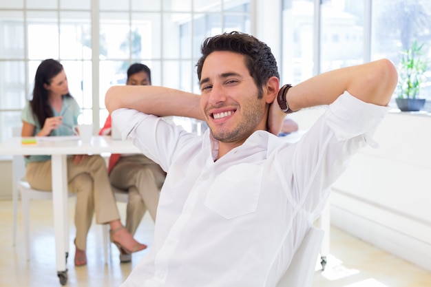 Empresário relaxando com colegas de trabalho em segundo plano