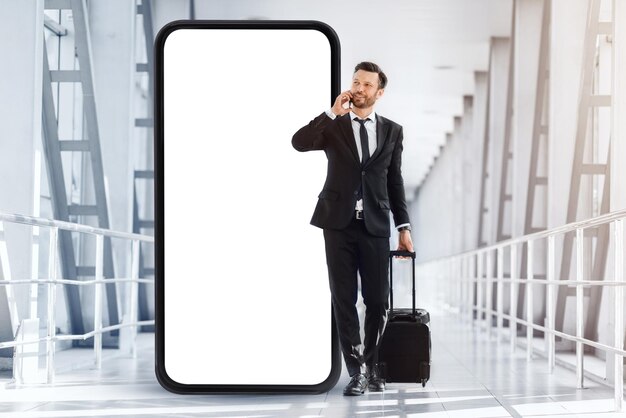 Empresário rico com mala andando pelo aeroporto tendo telefonema