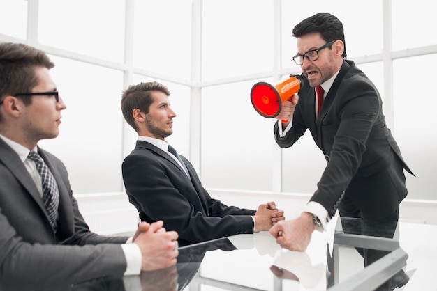 Empresário rigoroso com um megafone em uma reunião com funcionáriosa metáfora do negócio