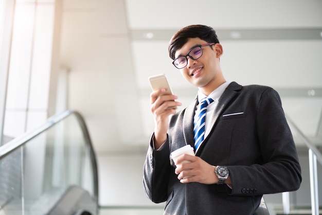 Empresário, segurando a xícara de café quente enquanto estiver usando o telefone. Conceito de negócios.