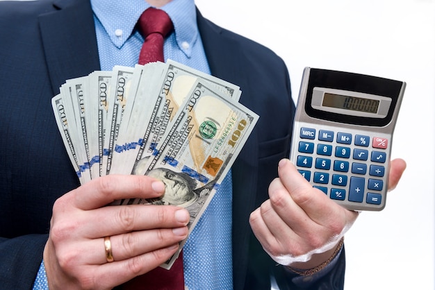 Empresário segurando dólares em leque e calculadora