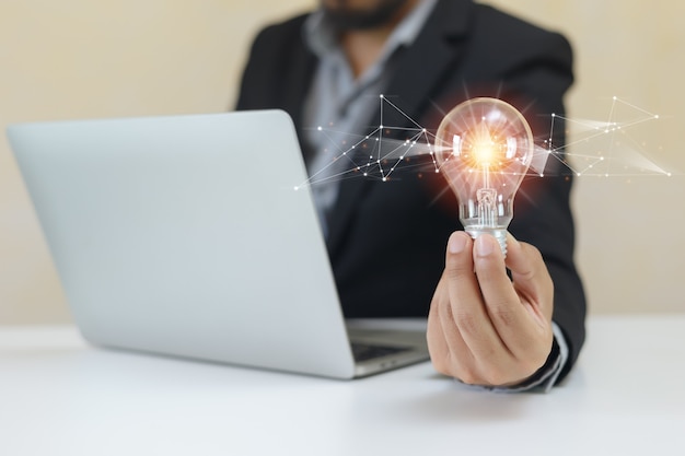 Empresário segurando lâmpadas usando o laptop. pense em inovação criativa. conceito de visão e ideias de poder.
