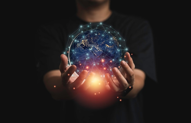 Empresário segurando mundo virtual com luz laranja e linha de conexão para o conceito global de telecomunicações.
