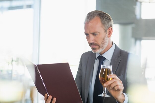 Empresário, segurando o copo de cerveja e olhando para o menu