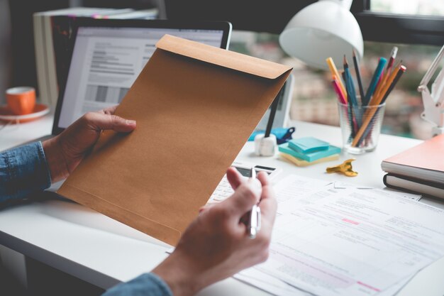 Empresário, segurando o envelope do documento sobre informações de table.business de mesa.