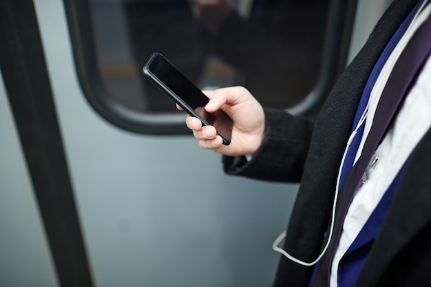 Empresário segurando smartphone no metrô