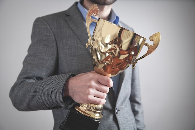 Empresário segurando troféu de ouro.