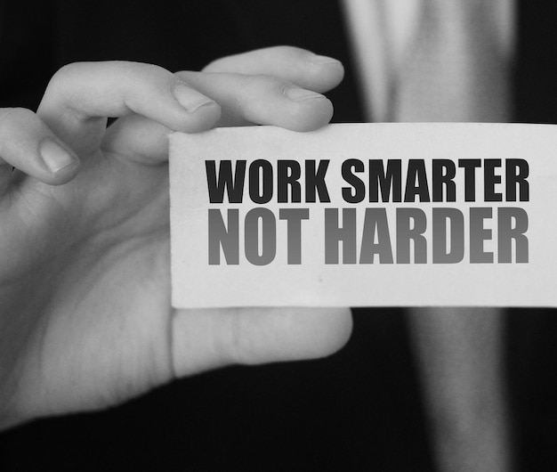 Empresário segurando um cartão com uma mensagem motivacional escrita nele Trabalhe de forma mais inteligente e não mais difícil
