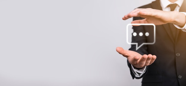 Empresário segurando um ícone de mensagem, bolha fala sinal de notificação em suas mãos. Ícone de bate-papo, ícone de sms, ícone de comentários, balões de fala
