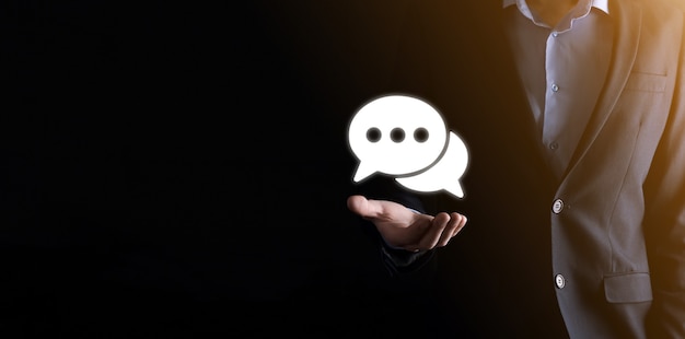 Empresário segurando um ícone de mensagem, bolha fala sinal de notificação em suas mãos. ícone de bate-papo, ícone de sms, ícone de comentários, balões de fala