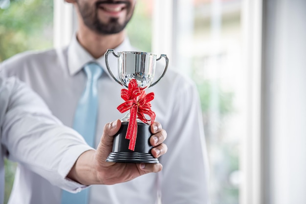 Empresário segurando um troféu e trabalhando para um objetivo