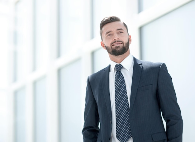 Empresario seguro de pie en una foto de oficina brillante con espacio para texto