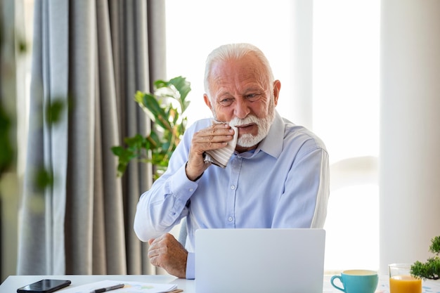 Empresário sênior chorando trabalhando e sentado o dia todo usando laptop ou notebook sofrendo dor de cabeça trabalhador doente conceito de excesso de trabalho