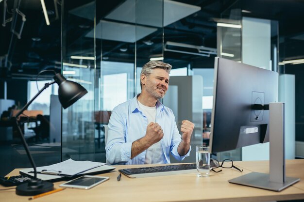 Empresário sênior e experiente parece frustrado com o monitor reclamando de baixo desempenho no trabalho