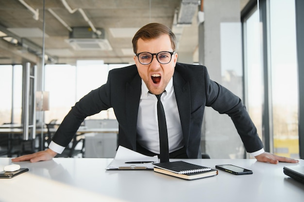 Foto empresario senior enojado sentado en su escritorio y gritando