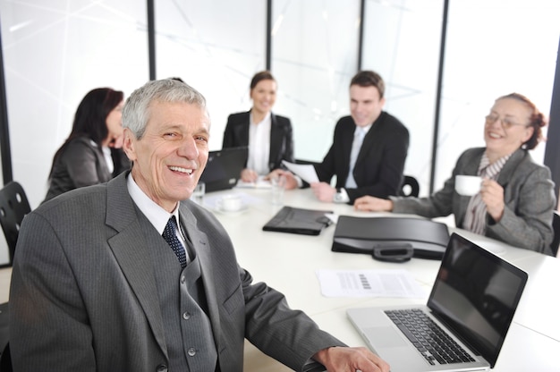 Empresario Senior en una reunión. Grupo de colegas en el fondo