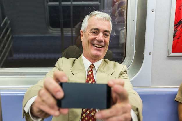 Empresario Senior tomando un Selfie en el metro