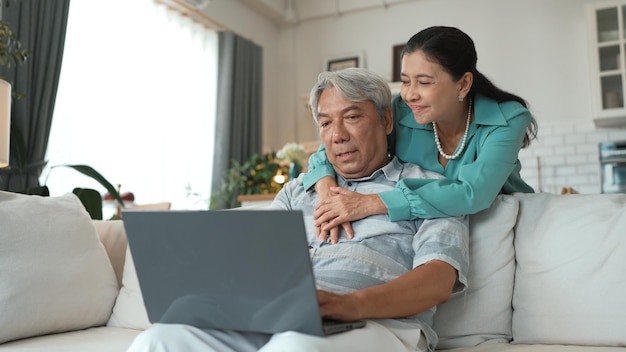 Empresario sénior trabajando en una computadora portátil mientras su abuela lo mantiene Myrmidon