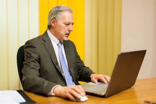 Empresario Senior trabajando en su escritorio en la oficina