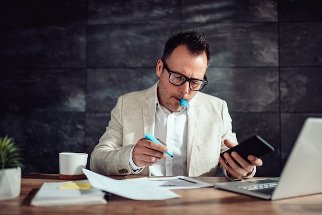 Empresário sentado em sua mesa e destacando o texto