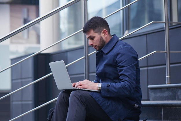 Empresário sentado na escada com laptop