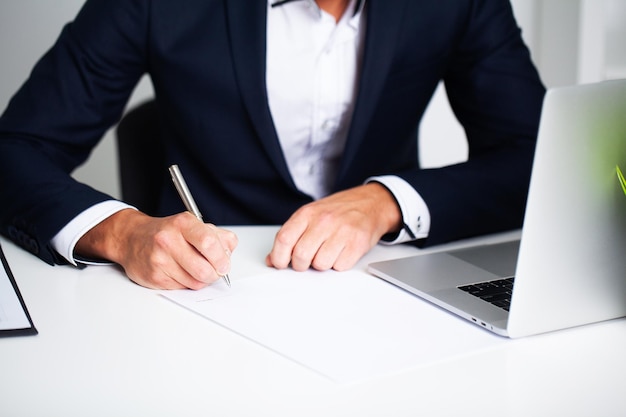 Empresário sentado na mesa de escritório, assinando contrato.