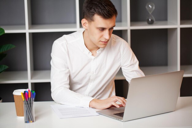 Empresário sentado na mesa de escritório trabalhando no computador portátil