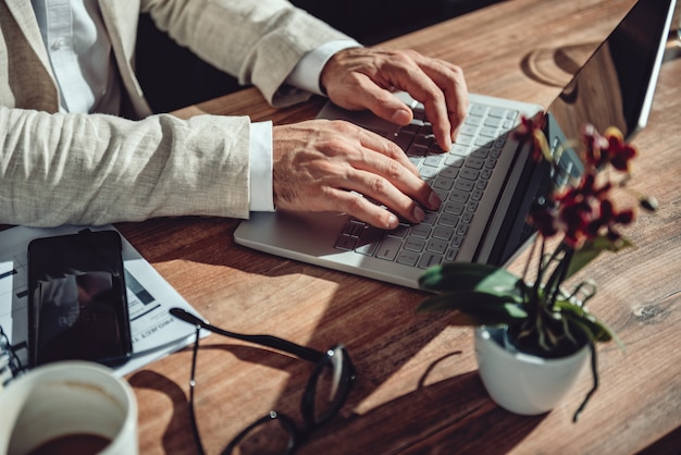 Empresario sentado en su escritorio y usando la computadora portátil en la oficina