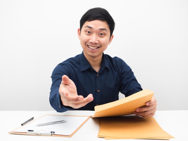 Empresário sente-se à mesa no local de trabalho segurando o envelope de documentos e dê a mão a você um sorriso feliz