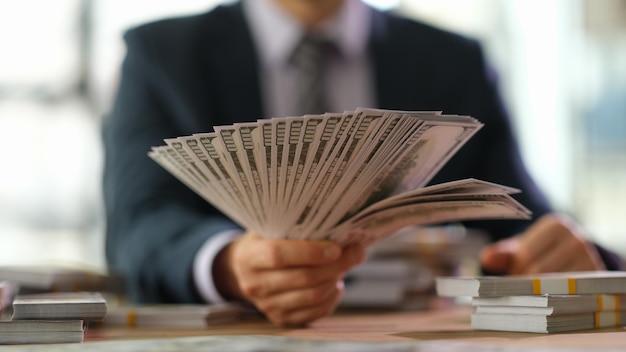 Empresario seo sosteniendo un abanico de dinero con billetes dispersos