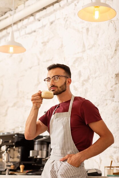 Empresario serio bebiendo capuchino en su cafetería