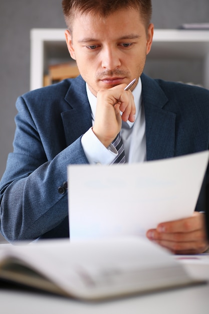 Foto empresario serio en la oficina examina documentos