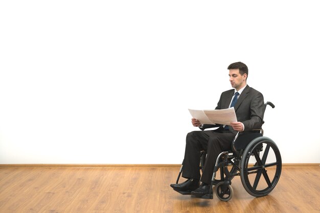 El empresario en silla de ruedas con papeles sobre el fondo de la pared blanca