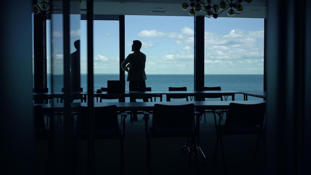 Empresario silueta viendo mar vista gran ventana empresario tomando descanso