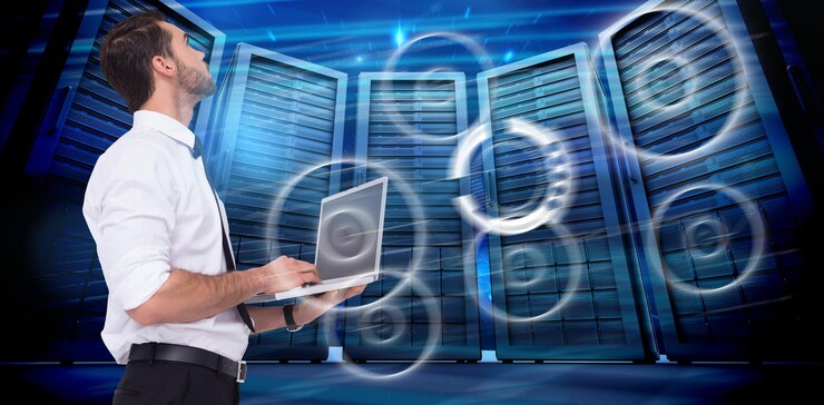 Foto empresario sofisticado de pie usando una computadora portátil contra la imagen compuesta de la sala de servidores