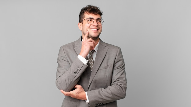 Foto empresario sonriendo felizmente y soñando despierto o dudando, mirando hacia el lado