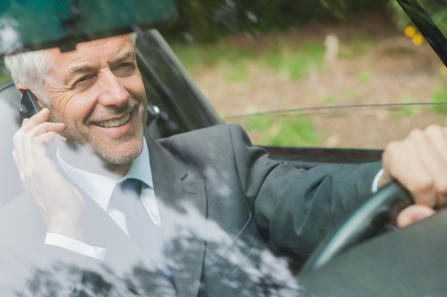 Empresario sonriente en la conducción del teléfono