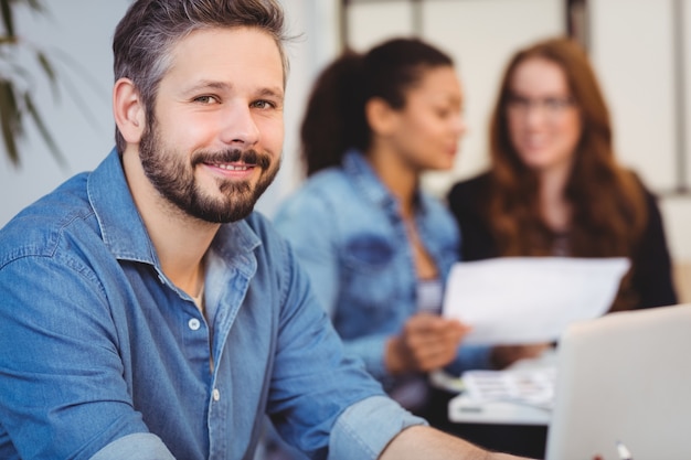 empresario sonriente contra compañeras de trabajo