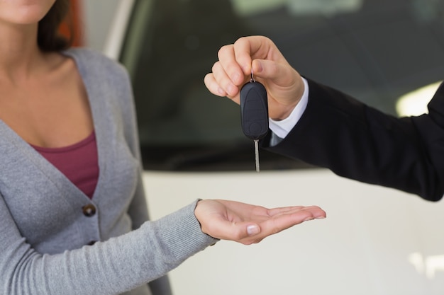 Empresario sonriente dando la llave del coche al cliente feliz