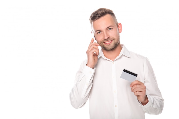 Empresario sonriente hablando por teléfono inteligente y con tarjeta de crédito aislado en blanco