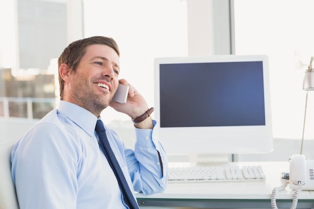 Empresario sonriente llamando a su escritorio